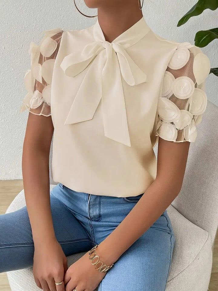 Elegant women’s blouse with a bow and sheer sleeves.